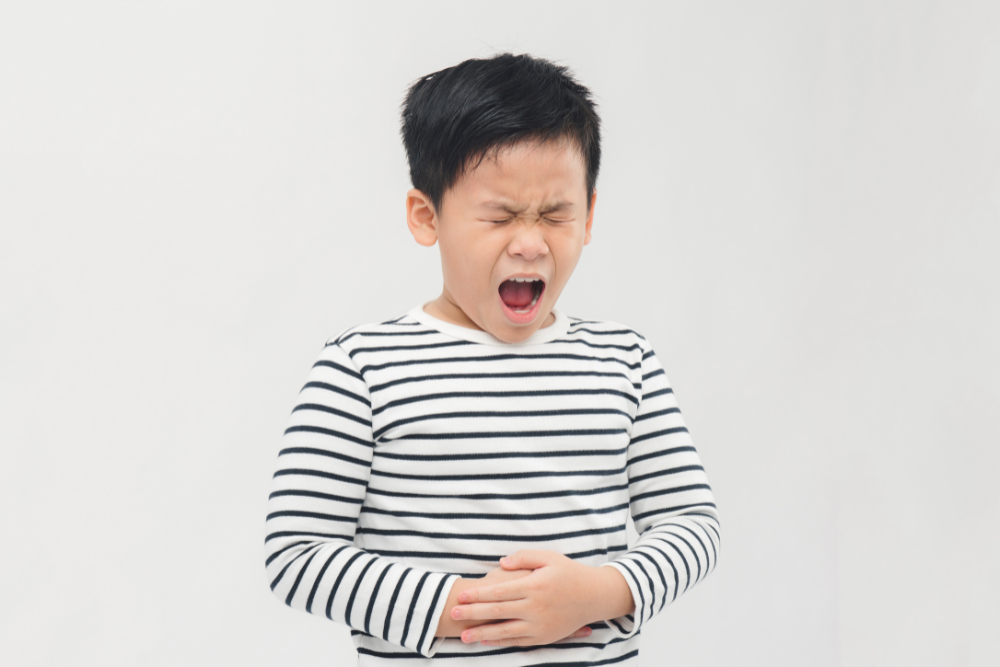Sad little boy suffering from stomach ache, holding his stomach, isolated on white background. 1